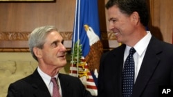 FILE - Former FBI Director James Comey talks with his predecessor, Robert Mueller, before Comey was officially sworn into office in Washington, Sept. 4, 2013.