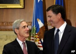 FILE - Former FBI Director James Comey talks with his predecessor, Robert Mueller, before Comey was officially sworn into office in Washington, Sept. 4, 2013.