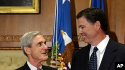 FILE - Former FBI Director James Comey talks with his predecessor, Robert Mueller, before Comey was officially sworn into office in Washington, Sept. 4, 2013.