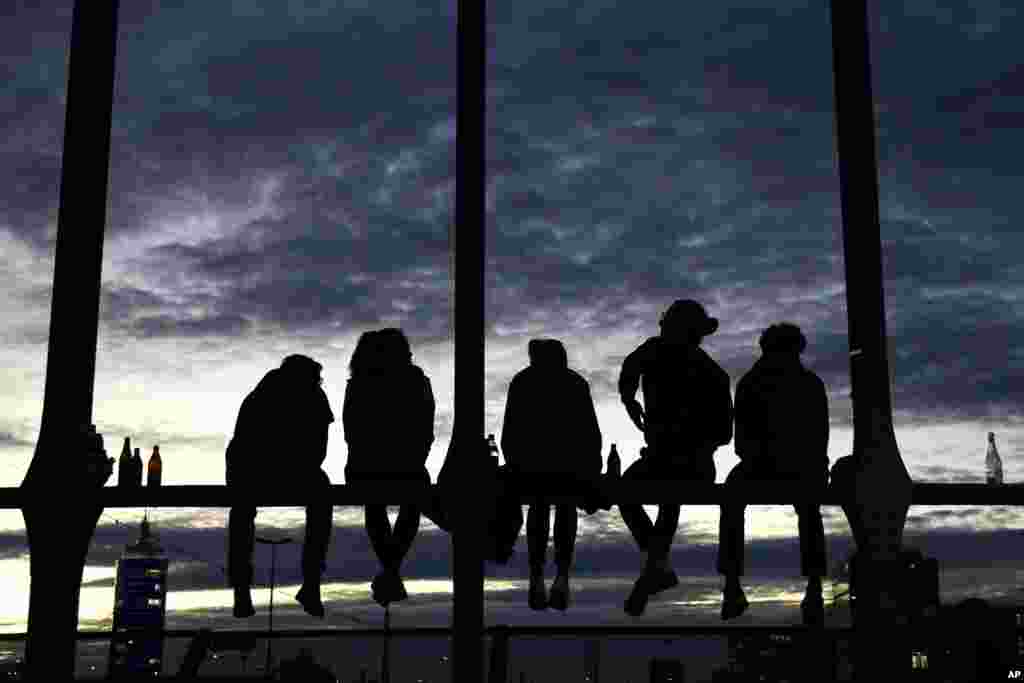 Young people enjoy a warm autumn evening sitting on the bridge 'Hackerbruecke' in Munich, Germany, Monday, Nov. 2, 2020. (AP Photo/Matthias Schrader)