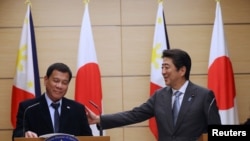 Philippine President Rodrigo Duterte (L) and Japan's Prime Minister Shinzo Abe attend a joint press conference at the prime minister's office in Tokyo, Japan October 26, 2016. REUTERS/Eugene Hoshiko/Pool