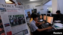 Journalist holds up a sample copy of The Voice Daily newspaper at a news room in Rangoon, March 31, 2013.