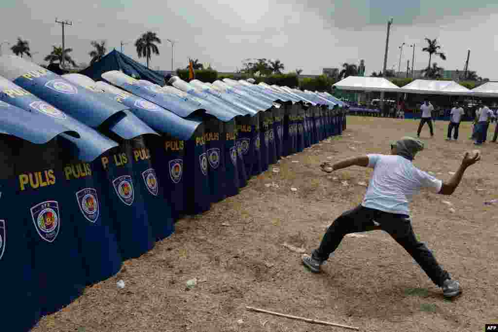 A mock protester throws a water bomb during police exercises to manage civil unrest in Manila, Philippines ahead of a visit by US President Barack Obama.
