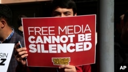 FILE - A protester is seen holding a placard at a rally in support of press freedom near the headquarters of a media company in Istanbul, Wednesday, Oct. 28, 2015.