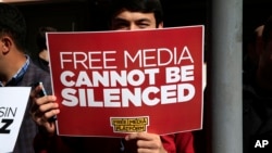 FILE - A protester is seen holding a placard at a rally in support of press freedom near the headquarters of a media company in Istanbul, Wednesday, Oct. 28, 2015.