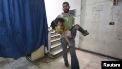 A man carries an injured girl in a field hospital after what activists say were air strikes by forces loyal to Syria's President Bashar al-Assad in Douma, eastern al-Ghouta, near Damascus, Syria, Oct. 17, 2014.