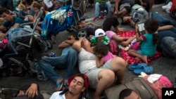 Members of a US-bound migrant caravan rest on a road between the Mexican states of Chiapas and Oaxaca after federal police briefly blocked them outside the town of Arriaga, Oct. 27, 2018. 