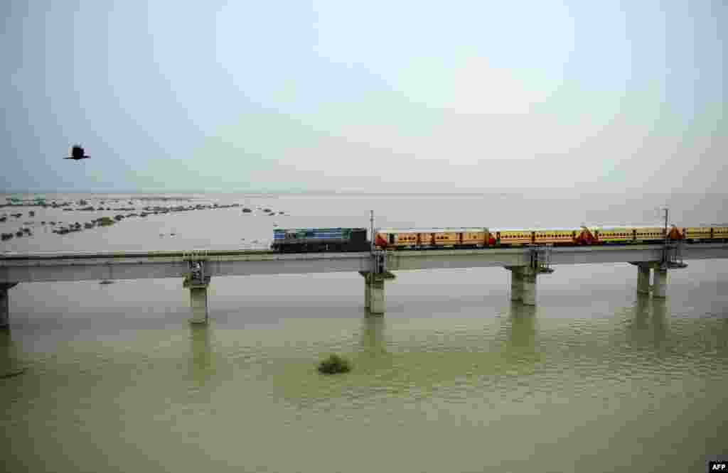 A train crosses a bridge over the flooded River Gange, as water levels in the Gange and Yamuna rivers rise, in Allahabad, India.