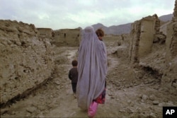 FILE - A widow carries her child home through a destroyed neighborhood in Kabul, Oct. 9, 1996.
