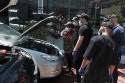Detailer mobil wanita Iran Maryam Roohani, kiri, membersihkan mobil yang menyemprotkan air saat peserta pelatihannya menonton, di sebuah bengkel detailing di Teheran, Iran, Minggu, 18 April 2021. (Foto: AP/Vahid Salemi)