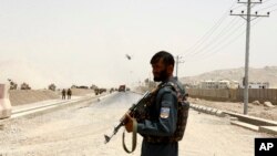 FILE - An Afghan policeman stands guard near the site of a suicide bomb attack on a NATO convoy in Kandahar, south of Kabul, Afghanistan, Aug. 2, 2017.