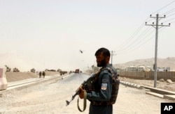 An Afghan policeman stands guard near the site of a suicide bomb attack on a NATO convoy in Kandahar, south of Kabul, Afghanistan, Aug. 2, 2017.