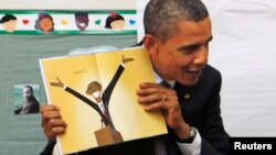 President AS Barack Obama memegang sebuah buku berisi gambar kartun dirinya, di sebuah kelas pertumbuhan anak-anak di Eastfield College di Mesquite, Texas. (Foto: Dok)