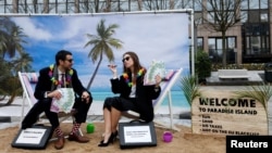 FILE - Activists stage a protest on a mock tropical island beach representing a tax haven outside a meeting of European Union finance ministers in Brussels, Belgium, Dec. 5, 2017. 