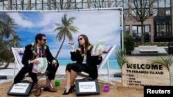 Activists stage a protest on a mock tropical island beach representing a tax haven outside a meeting of European Union finance ministers in Brussels, Belgium, Dec. 5, 2017. 