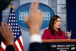 White House press secretary Sarah Huckabee Sanders answers a question as reporters raise their hands during the daily news briefing at the White House, Feb. 20, 2018, in Washington.