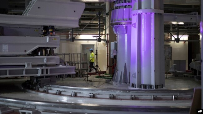 Un trabajador camina a través de grandes herramientas de montaje en la sala de montaje del ITER (Reactor Termonuclear Experimental Internacional).  El proyecto tiene como objetivo replicar la energía del sol para crear reacciones de fusión nuclear como una forma de producir energía.  (Foto AP)