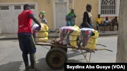 Un marchad achemine des packs de fripes sur un chariot des magasins vers le marché pour la vente au détail à Colobane, 17 juin 2017. (VOA/ Seydina Aba Gueye)