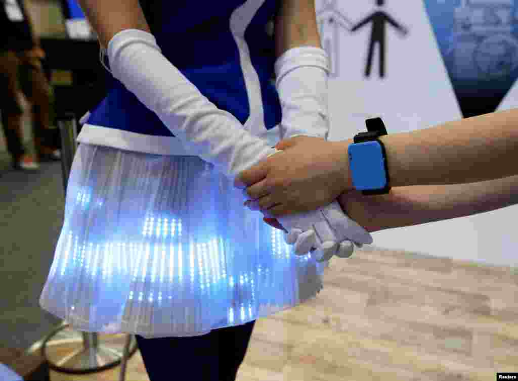 Women demonstrate Panasonic's Human Body Communication Device, which changed the color of the LEDs on a cloth to same color of the wrist device, at CEATEC (Combined Exhibition of Advanced Technologies) JAPAN 2016, at the Makuhari Messe in Chiba, Japan.