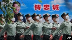 北京街头一队武警士兵走过习近平的宣传画。（2020年5月25日）