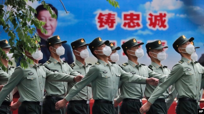 资料照：守卫北京天安门的中国军队士兵走过宣传习近平领导的宣传画。（2020年5月25日）