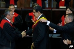 FILE - Venezuela's President Nicolas Maduro, center, shakes hands with Supreme Court President Maikel Moreno as his presidential sash is adjusted, after he took the oath of office in Caracas, Jan. 10, 2019. Maduro's second, six-year term starts amid internationa