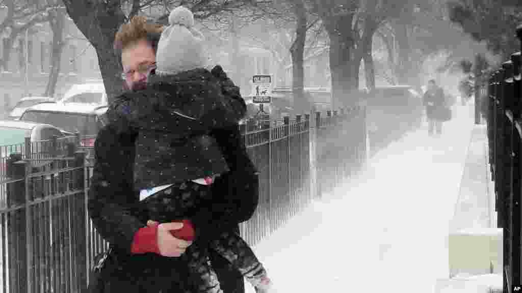 Avec un enfant dans les bras, un homme brave la neige à Chicago, le 14 mars 2017.