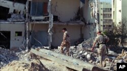 FILE – Days after the June 25, 1996, truck bombing of a housing complex that killed 19 U.S. airmen, a Saudi and a U.S. serviceman visit the site in Dhahran, Saudi Arabia. The attack's alleged mastermind reportedly has been arrested.
