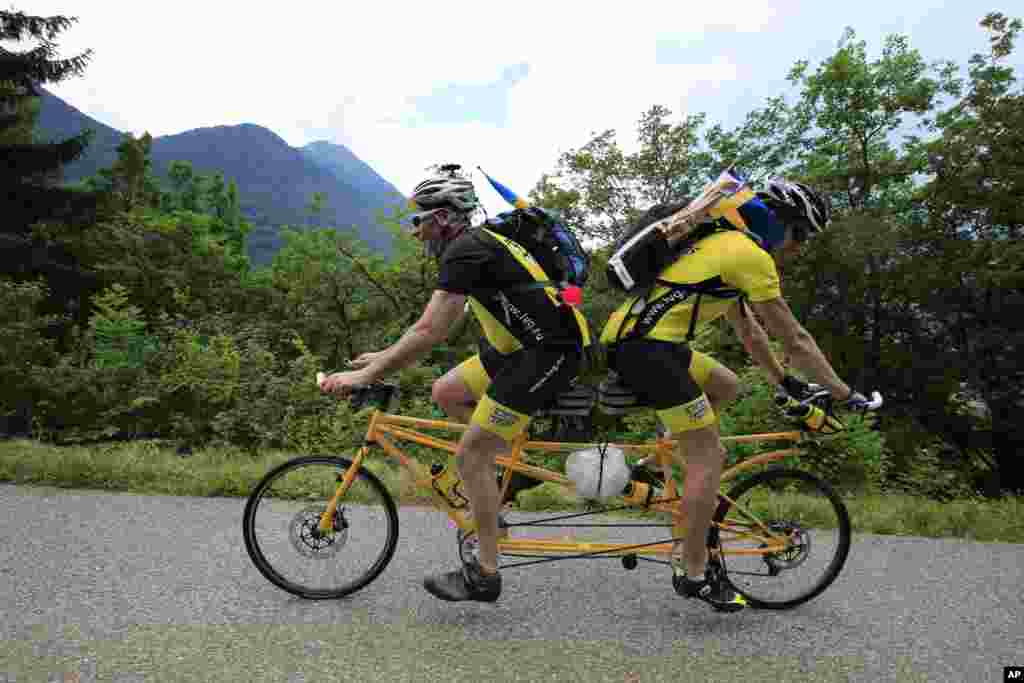 Sweden&#39;s Ake Johansson, left, and a friend climb L&#39;Epine pass on a self-made tandem bicycle during the 19th stage of the Tour de France. 