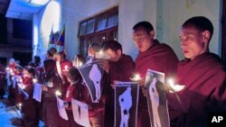 January 25, 2012, file photo shows Tibetan Buddhist monks holding pictures of Tibetans they claim were allegedly shot by Chinese security forces earlier this week, during a candlelight vigil in Dharamsala, India