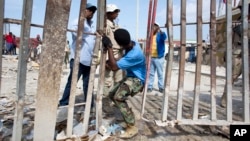 FILE - Dominican authorities push a man back into the Haitian side of the border at the fence separating the Dominican Republic town of Jimani and the Haitian town of Malpasse, Aug. 26, 2015.