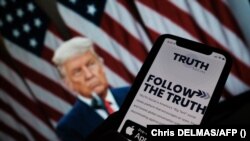 Foto ilustrasi yang menunjukkan seseorang memeriksa aplikasi media sosial buatan perusahaan mantan presiden Donald Trump bernama "Truth Sosial" dalam telepon genggam miliknya. (Foto: AFP/Chris Delmas)