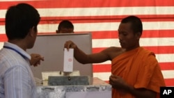 Cambodian Buddhist monk, right, casts his ballot in local elections at Wat Than pagoda's polling station in Phnom Penh, Cambodia, Sunday, June 3, 2012. Prime Minister Hun Sen's ruling party was expected to win the elections in a vote that monitors say is tainted by vote buying and other irregularities. (AP Photo/Heng Sinith)