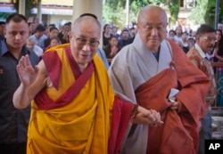 FILE - Tibetan spiritual leader the Dalai Lama, left, greets devotees as he arrives to give a talk at the Tsuglakhang temple in Dharmsala, India, Sept. 7, 2015.