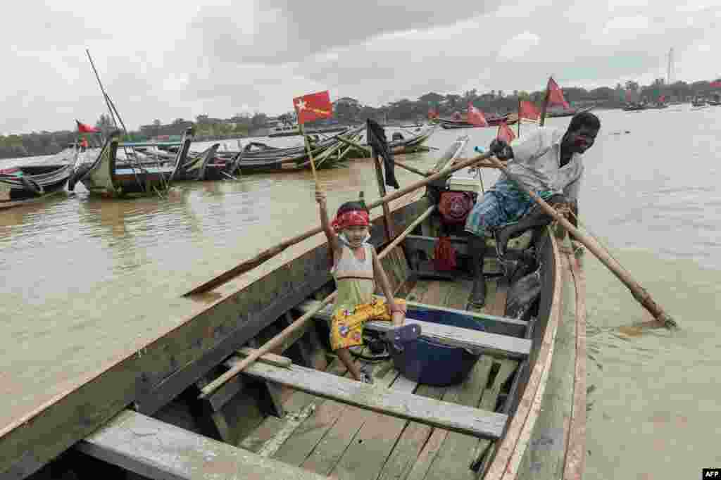A child holds an emblem of the National League for Democracy as supporters ride on wooden boats in Yangon River, during an election campaign rally on the outskirts of Yangon, ahead of next month's elections.