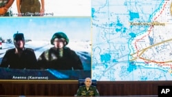 Lt.-Gen. Sergei Rudskoi, center, of the Russian Military General Staff listens to Russian and Syrian officers during a video call, as a Syrian army facility is displayed on screen, at a Russian Defense Ministry building in Moscow, Russia, Sept. 12, 2016. Rudskoi said that the Russian military will continue strikes against the Islamic State group and the al-Qaida's branch in Syria.