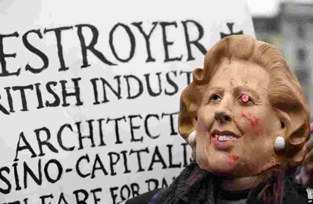Seorang pengunjuk rasa mengenakan topeng wajah mantan PM Inggris Margaret Thatcher dalam pesta yang digelar untuk menandai kematiannya di lapangan Trafalgar, pusat London, Sabtu (13/4).