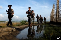 FILE - Myanmar police officers patrol along the fence bordering Bangladesh in Maungdaw, Rakhine State, Myanmar, Oct. 14, 2016.