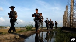FILE - Myanmar police officers patrol along the fence bordering Bangladesh in Maungdaw, Rakhine state, Myanmar, Oct. 14, 2016. Myanmar's government says the latest fighting was triggered by an ambush on police Saturday.
