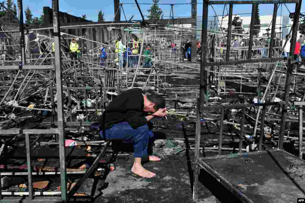 A man holds his head in his hands as he sits among bed frames burned by a fire which tore through a refugee camp in Diavata, northern Greece, threatening the lives of over 2,300 people who live there. More than a dozen tents were destroyed in the blaze.