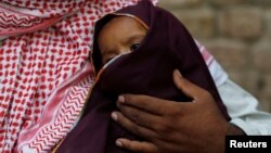 Two-year-old HIV positive boy sits on the lap of his father, in Ratodero, Pakistan May 24, 2019. (REUTERS/Akhtar Soomro)