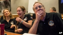 Members of the New Horizons science team react to seeing the spacecraft's last and sharpest image of Pluto before closest approach later in the day, at the Johns Hopkins University Applied Physics Laboratory (APL) in Laurel, Maryland, July 14, 2015. 