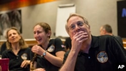 Members of the New Horizons science team react to seeing the spacecraft's last and sharpest image of Pluto before closest approach later in the day, at the Johns Hopkins University Applied Physics Laboratory (APL) in Laurel, Maryland, July 14, 2015 .