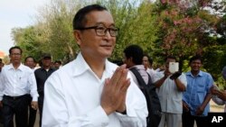 Cambodian main opposition Cambodia National Rescue Party leader Sam Rainsy, front, greets his supporters as his arrives at Choeung Ek memorial on the outskirts of Phnom Penh, Cambodia, Friday, May 17, 2015. Sam Rainsy on Friday led a Buddhist ceremony mar