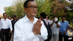 Cambodian main opposition Cambodia National Rescue Party leader Sam Rainsy, front, greets his supporters as his arrives at Choeung Ek memorial on the outskirts of Phnom Penh, Cambodia, Friday, May 17, 2015. 