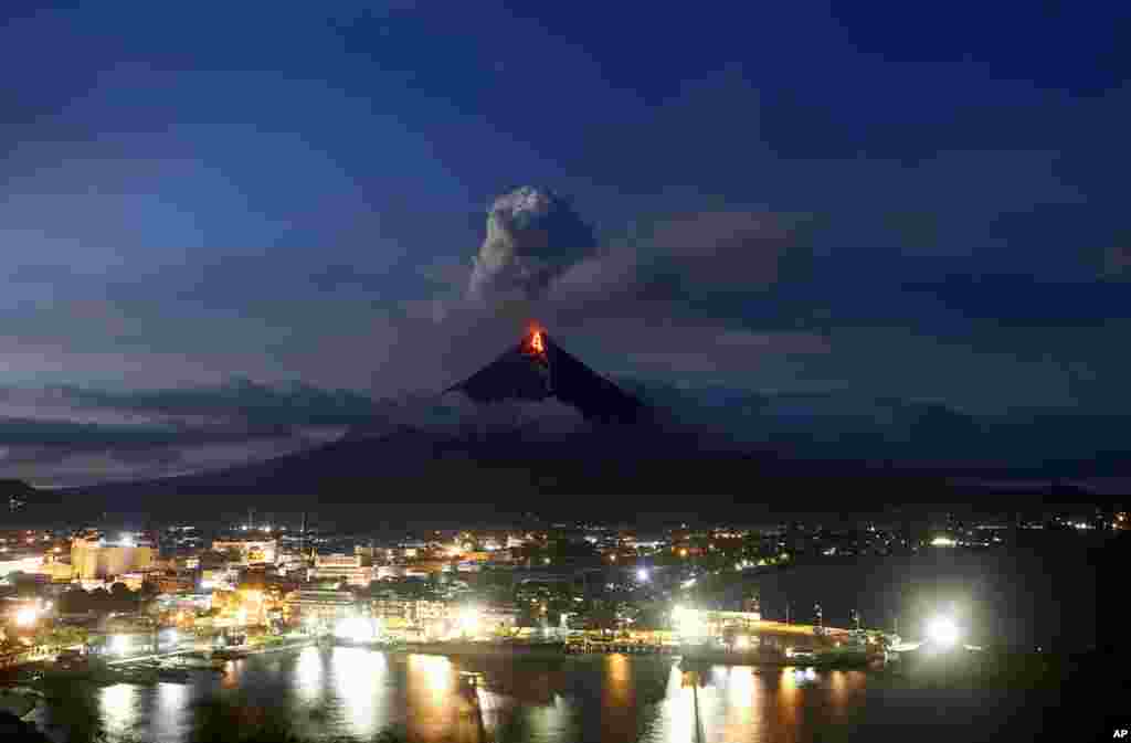 The Mayon volcano continues to erupt, Jan. 25, 2018, as the sun sets behind Legazpi city, in Albay province, roughly 340 kilometers, (200 miles) southeast of Manila, Philippines.