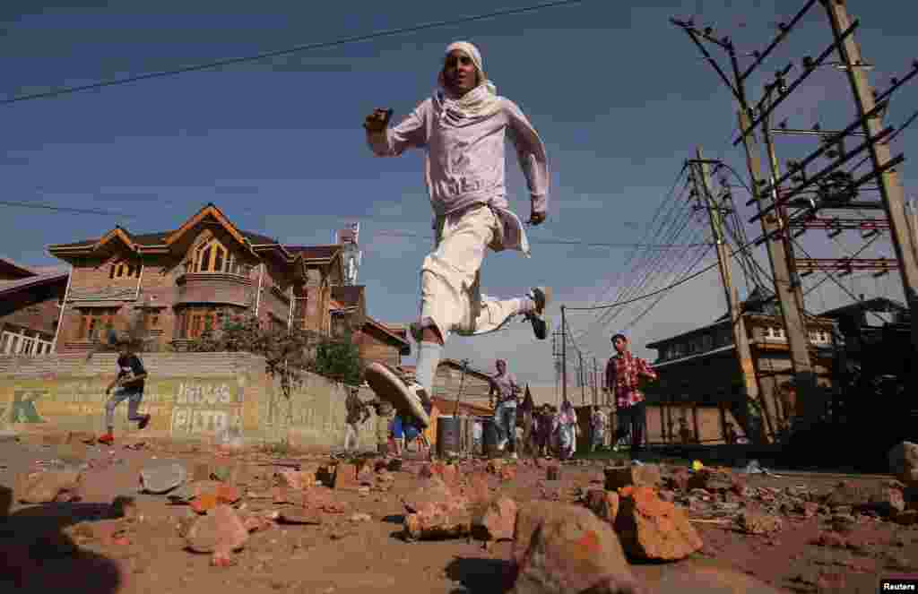 Kashmiris run for cover as Indian security forces (not pictured) fire tear gas shells during clashes, after scrapping of the special constitutional status for Kashmir by the Indian government, in Srinagar.