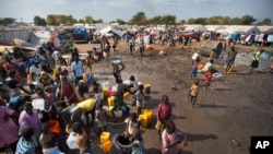 FILE - Displaced people are seen gathered around a water truck to fill containers at a United Nations compound which has become home to thousands of people displaced by fighting, in the capital Juba, South Sudan.