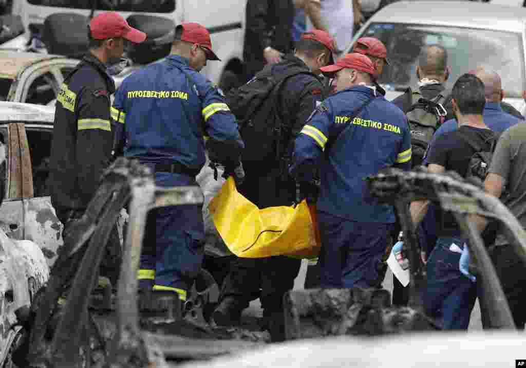 Firefighters remove a dead body that was killed in wildfires in Mati east of Athens, Tuesday, July 24, 2018.