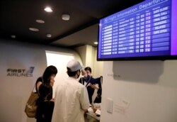 A staff dressed as a flight attendant checks temperature of a customer at a check-in desk at First Airlines amid the COVID-19 pandemic in Tokyo, Japan August 12, 2020. (REUTERS/Kim Kyung-Hoon)